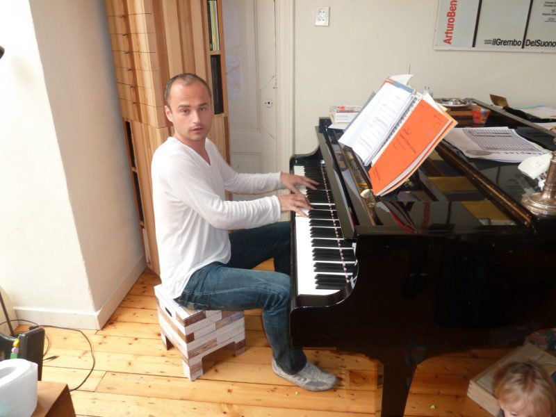 Tim zit op een festivalchair terwijl hij piano speelt